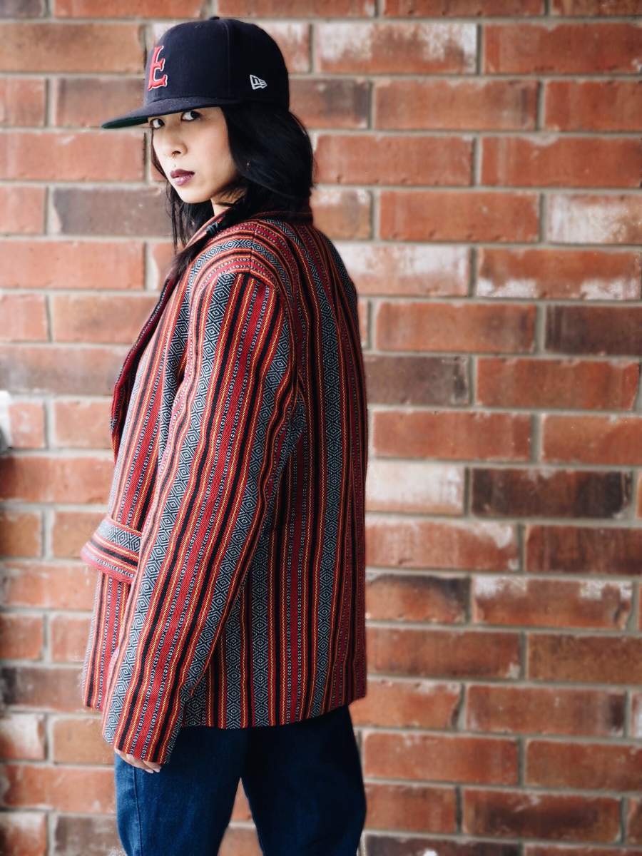 VINTA Unisex Oversized Ifugao Jacket, side view, unbuttoned, styled with baseball cap, and blue jeans
